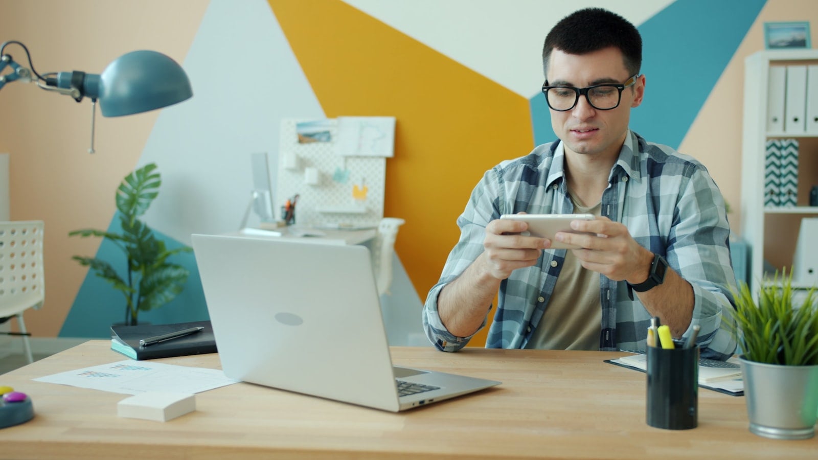 Man playing video game on phone at desk.