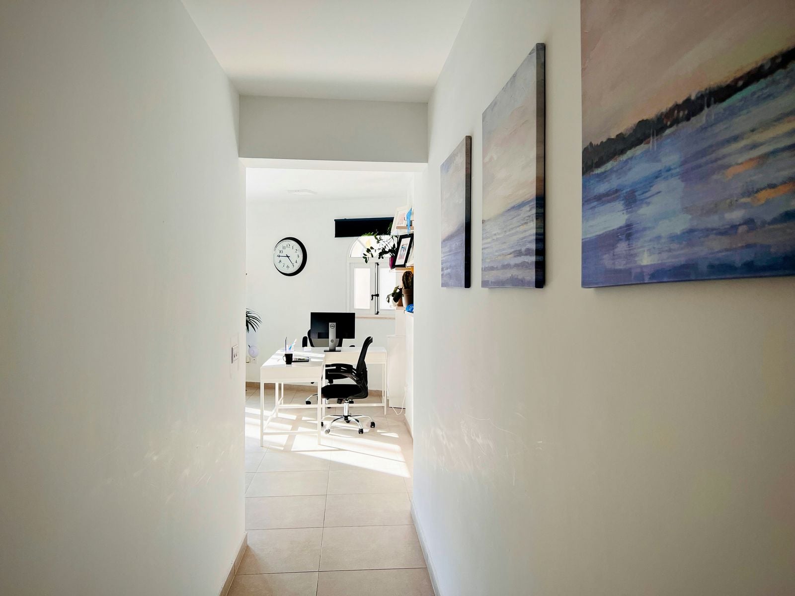 Hallway leading to a bright office with artwork