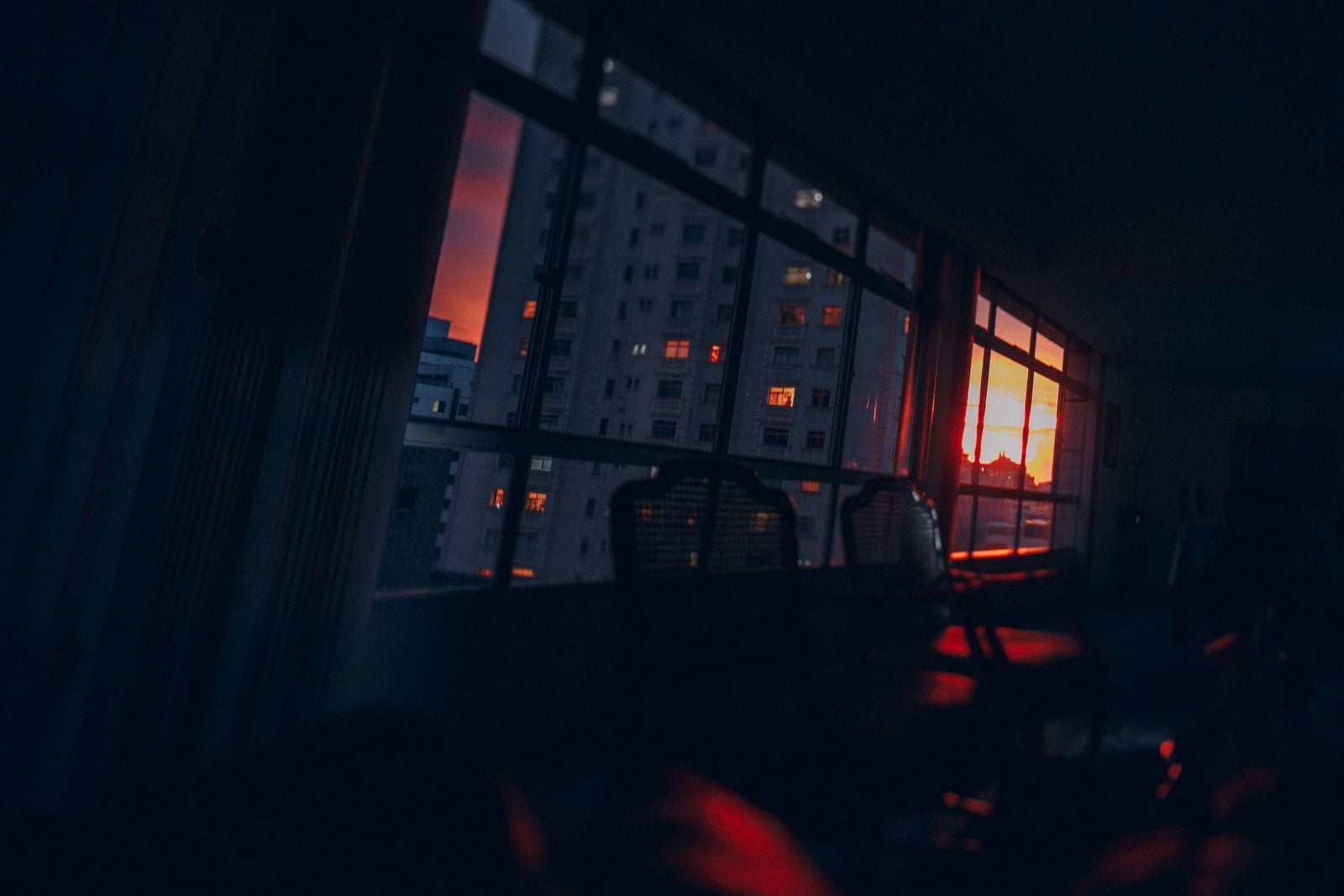 Sunset seen through a window overlooking city buildings.